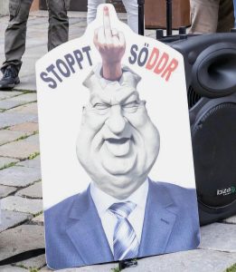 A 67-year-old retired Bavarian woman was found guilty of insulting a public official and must pay an €800 fine for displaying a caricature of Markus Söder during a protest against COVID-19 policies. ( source private)